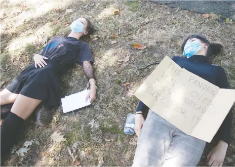  ?? MIKE BELL ?? Grace Hodges, left, and Elena Massing were among about two dozen New Westminste­r Secondary School students who participat­ed in a `die-in' Tuesday near the school board offices.