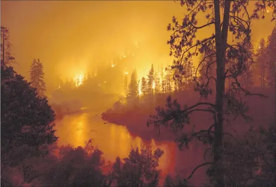  ?? David McNew AFP/Getty Images ?? FLAMES FROM the McKinney fire, fueled by winds, scorch the terrain along the Klamath River this week in the Klamath National Forest northwest of Yreka, Calif.