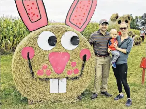  ?? DESIREE ANSTEY/ JOURNAL PIONEER ?? Jana Arsenault, her two-year-old son, Johnathon, and husband Mike admire the towering hay sculpture at Kool Breeze Farms during the Scarecrow Festival on Sunday.