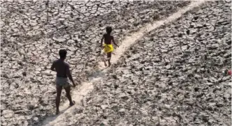  ?? AP PHOTO/MANISH SWARUP ?? A man and a boy walk across the almost dried up bed of the Yamuna river May 2 following hot weather in New Delhi, India.