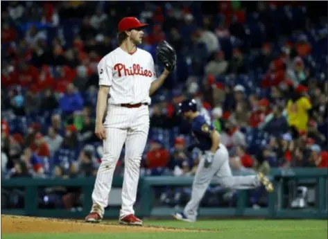  ?? MATT SLOCUM – THE ASSOCIATED PRESS ?? Phillies starting pitcher Aaron Nola, left, waits for a fresh ball after giving up a home run to Milwaukee Brewers’ Mike Moustakas, right, during the third inning Monday night at Citizens Bank Park.