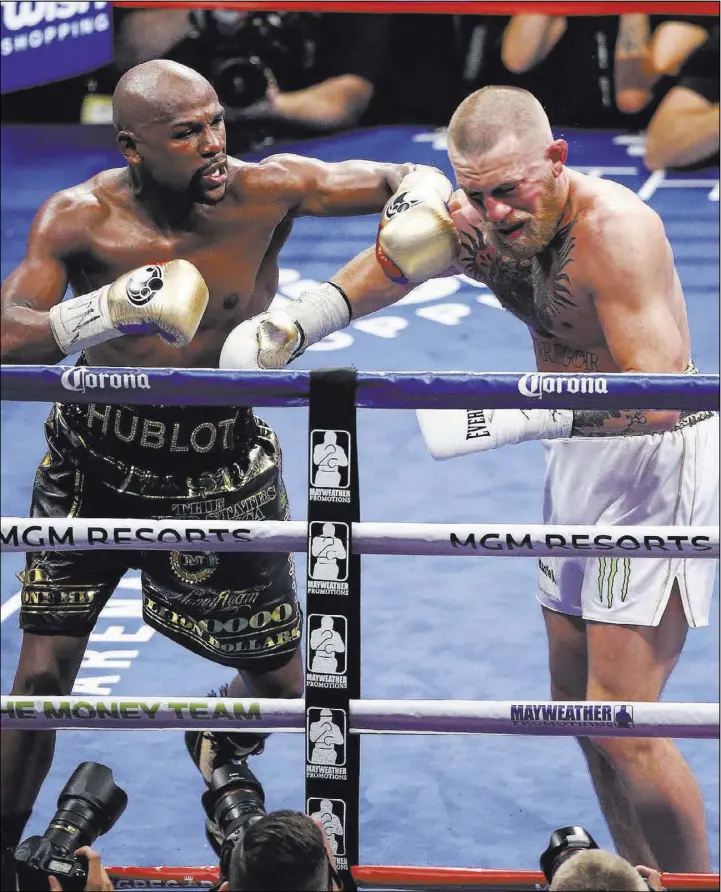  ?? Chase Stevens Las Vegas Review-Journal @csstevensp­hoto ?? Floyd Mayweather, left, delivers the final blows to MMA star Conor McGregor in their 154-pound fight Saturday at T-Mobile Arena. Mayweather won by 10th-round TKO.