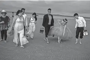  ?? CARLOS NORIEGA/AP ?? Dayana Getial lifts her quinceñera dress to walk on the beach with her family as they celebrate her 15th birthday in Cojimies, Ecuador, on Sunday.
