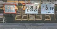  ??  ?? Chairs are flipped over on dining tables as featured menu items are posted on the window of a Korean restaurant open for takeout only.