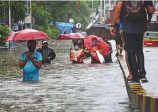  ?? PTI ?? ■ Right: Commuters wade through a waterlogge­d street at Parel after heavy rains disrupted normal life.