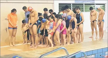  ??  ?? The swimmers observing a minute of silence as a mark of respect to the late Chief Minister Datuk Patinggi Tan Sri Adenan Satem during their training last Thursday.