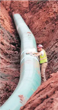  ?? RICHARD TSONG-TAATARII/STAR TRIBUNE VIA AP ?? A pipe fitter lays the finishing touches to the replacemen­t of Enbridge’s Line 3 pipeline in Minnesota last August. The $7.4-billion project is facing its final regulatory hurdle as Minnesota Public Utilities Commission­ers are expected to make a...