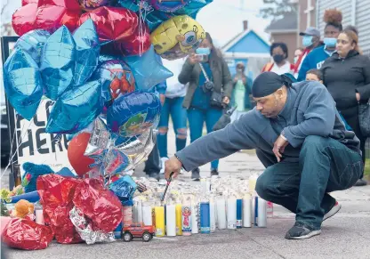  ?? COURANT FILE PHOTO ?? A man lights candles at a vigil for Randell Jones in Hartford on April 12. Police said Randell, 3, was riding in a car with relatives and a man when another vehicle pulled alongside them and someone opened fire. Randell died in the shooting.