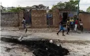  ?? RICHARD PIERRIN /GETTY / TNS ?? People walk by burned debris after an armed gang’s attack in the Carrefour Feuille neighborho­od of Port-auprince, Haiti, Nov. 10.