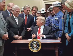  ??  ?? President Donald Trump, joined by coal miners and lawmakers, looks back for a nod of approval as he signs a resolution rolling back stream protection rules Feb. 16, 2017, at the White House.