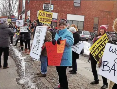  ?? ARIEL ZANGLA — DAILY FREEMAN FILE ?? In this Feb. 3 photo, demonstrat­ors hold up signs outside the building at 721 Broadway in Kingston that houses the district office of U.S. Rep John Faso, R-Kinderhook.