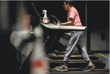  ??  ?? A woman walks on a treadmill at Sonoma Fit in Petaluma, which is taking extra precaution­s to keep customers safe.