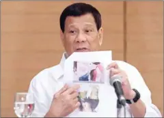  ?? MANMAN DEJETO ?? Philippine President Rodrigo Duterte shows a photo of a Filipina worker in Kuwait, of whom he said had been ‘roasted like a pig’, during a press conference in Davao City, in the southern island of Mindanao on Friday.