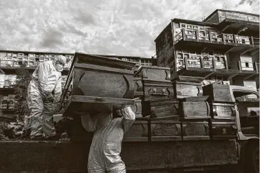  ?? Esteban Felix / Associated Press ?? Workers collect and stack the coffins of people that have been cremated amid the coronaviru­s pandemic at the La Recoleta cemetery in Santiago, Chile, on Sunday. The coffins will then be destroyed and processed.
