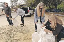  ?? Al Seib Los Angeles Times ?? AIMING to protect her Montecito home, Candra Emmeluth, right, gets help Tueday from daughter Jamie as son Brett, left, fills sandbags with daughter Curyn.