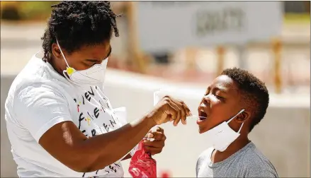  ?? AL SEIB / LOS ANGELES TIMES / TNS ?? Cynthia Leonard helps her son Messi McDaniel, 6, with the oral swab test during COVID-19 testing at the Charles R. Drew University of Medicine and Science in South Los Angeles in July.