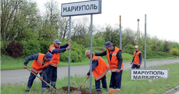  ?? ?? I cartelli in lingua russa Alcuni operai municipali rimuovono il segnale di ingresso a Mariupol in lingua ucraina e collocano al suo posto quello in lingua russa (Afp)