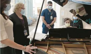  ?? ?? Volunteer pianist Renee Mullaney plays the piano as staffers listen.