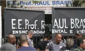  ??  ?? Police officers guard the entrance of the Raul Brasil school. About 1,000 children attend the school, police said. Photograph: Mauricio Sumiya/AP