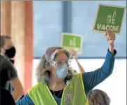  ?? TED S. WARREN / AP ?? Sally Avenson, a nurse working as a volunteer at a mass vaccinatio­n clinic at Seattle University, holds up a sign to indicate she needs more doses of the Moderna COVID-19 vaccine at her station.