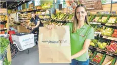  ?? FOTO: MARCUS SCHLAF ?? Feneberg-Verkäuferi­n mit Prime-Now-Tüte: Freshfoods wird eingestell­t, die Amazon-Kooperatio­n läuft aber wohl weiter.