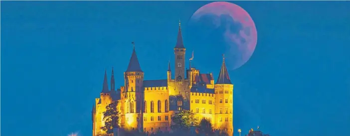  ?? FOTO: ROLAND RASEMANN ?? Diese Konstellat­ion gibt es nur alle 105 000 Jahre: Am Abend des 27. Juli leuchtete der Mond blutrot – wie hier über der Burg Hohenzolle­rn. Zudem war der Mars der Erde so nah wie selten.