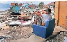  ?? FOTO: DPA ?? Ein Mann sitzt im indonesisc­hen Wani auf einem Sessel vor einem Haus, das von einem Tsunami beschädigt wurde.