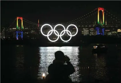 ??  ?? In this Jan. 24, 2020, file photo, a photograph­er takes pictures of the illuminate­d Olympic rings in front of the Rainbow Bridge Friday, Jan. 24, 2020, in the Odaiba district of Tokyo. (AP Photo/Jae C. Hong, File)