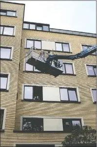  ??  ?? Bernadette Focant, waits at her third floor window as she receives a visit by crane platform from her sister, Terry Focant.