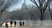  ?? REBECCA BLACKWELL/AP ?? People stroll past a section of the National Mall by the Capitol where workers were dismantlin­g inaugurati­on installati­ons after most downtown streets and spaces had reopened to the public Saturday in Washington.
