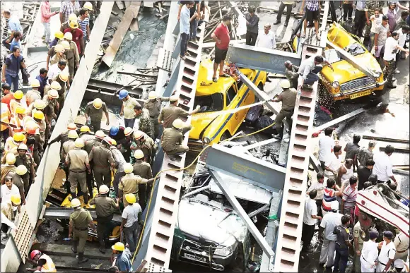  ??  ?? Indian rescue workers work on a partially collapsed overpass in Kolkata, India, on March 31. A long section of a road overpass under constructi­on collapsed Wednesday in a crowded Kolkata neighborho­od, with
tons of concrete and steel slamming into...