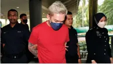  ?? – Bernama photo ?? Foo is escorted by police at the court.