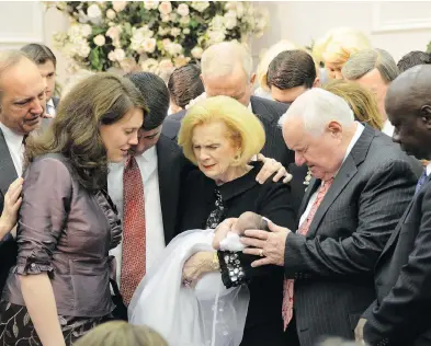  ?? THE ASSOCIATED PRESS FILES ?? In this 2012 photo provided by a former member of the church, Word of Faith Fellowship leader Jane Whaley, centre, holds a baby, accompanie­d by her husband, Sam, centre right, at a ceremony in the church’s compound.