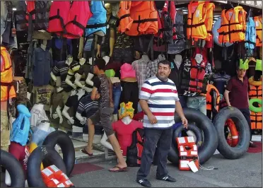  ??  ?? Massive influx: A stall-holder in Turkey selling life jackets to migrants headed for Greece