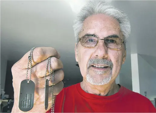  ?? Ryan Remior z / THE CANADIAN PRESS ?? Jack Todd, who deserted to Canada to avoid the Vietnam War, holds up his dog tags in his home in Greenfield Park, Que.