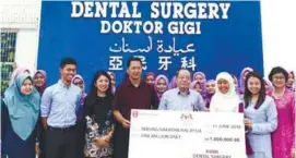  ??  ?? DAP adviser Lim Kit Siang (centre) posing with a mock cheque and Amim Dental Surgery staff.