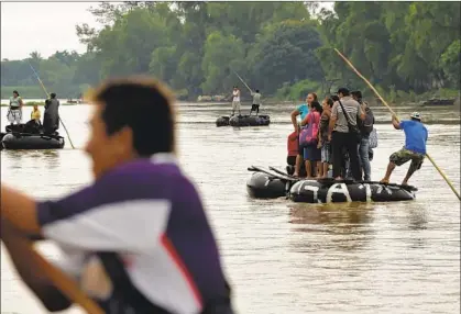  ?? Alfredo Estrella AFP/Getty Images ?? MIGRANTS use makeshift rafts to cross the Suchiate River along Guatemala’s border with Mexico last month.