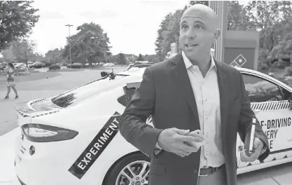  ?? PHOTOS BY ELAINE CROMIE, SPECIAL TO THE DETROIT FREE PRESS, VIA USA TODAY NETWORK ?? Domino’s Chief Developmen­t Officer Kelly Garcia stands next to the Ford Fusion self-driving hybrid that will be used as a test pizza delivery vehicle in Ann Arbor, Mich.