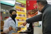  ?? DAKE KANG — THE ASSOCIATED PRESS ?? Staff sell masks at a Yifeng Pharmacy in Wuhan, Chin, Wednesday. Pharmacies in Wuhan are restrictin­g customers to buying one mask at a time amid high demand and worries over an outbreak of a new coronaviru­s.