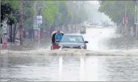  ?? SANJEEV KUMAR/HT ?? A car passing through a waterlogge­d road after rain in Bathinda on Friday.