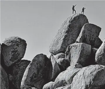  ?? MARIO TAMA/GETTY ?? Rock climbers stand Friday on top of a formation at Joshua Tree National Park, which has remained open during the shutdown. Campground­s at the California park have closed.