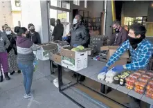  ?? Andy Cross, The Denver Post ?? Co- owner of Emerald Gardens Microgreen­s, Roberto Meza, right, organizes eggs and vegetables to be sold Wednesday at the Lost City Market. Meza formed the East Denver Food Hub, which sells produce to people in need who pay only what they can afford.