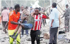  ??  ?? Civilians assist a man injured from a suicide car bomb explosion in Mogadishu, Somalia. (Reuters)