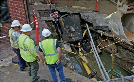  ?? MATT STONE pHOTOS / HERALd STAff ?? HANCOCK STREET HOLE: Workmen stand around a huge hole on Hancock Street where a water main broke, sending flood waters into people’s homes on Beacon Hill on Tuesday.