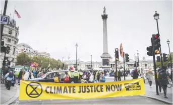  ??  ?? An Extinction Rebellion banner blocks the road to Trafalgar Square in London last October. The protest came weeks after millions took to the streets to urge leaders to take decisive action on climate change.
BLOOMBERG