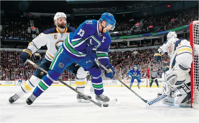  ?? JEFF VINNICK/NHLI VIA GETTY IMAGES ?? Buffalo defenceman Mike Weber, left, and goaltender Matt Hackett combine to knock the puck off the stick of Henrik Sedin during the Canucks’ 5-2 win over the Sabres on Friday at Rogers Arena.