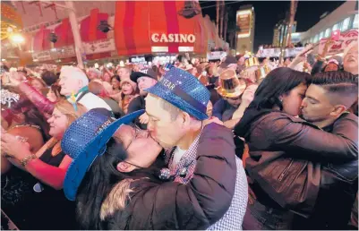  ?? MARCUS/LASVEGAS SUN2018 STEVE ?? At center-left, newlyweds Alison and Kenny Finchum, of Tulsa, Oklahoma, kiss during a NewYear’s party at the Fremont Street Experience in Las Vegas. Plans for a 14,000-person street party are facing pushback from state and local officials.