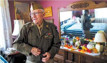  ?? STAFF PHOTO BY DOUG STRICKLAND ?? Thomas Rollins puts on his Army uniform in the bedroom of his home Oct. 26 in Altamont, Tenn. Rollins is a veteran of the United States Army who served with the 28th Infantry Division in the European theater during World War II.