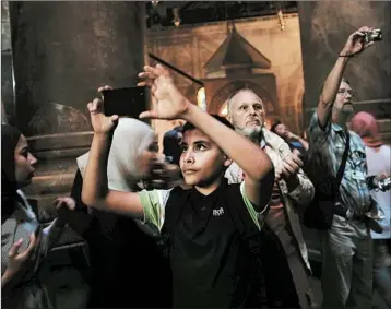  ?? SPENCER PLATT/GETTY IMAGES ?? Tourists snap photos in the Church of the Holy Sepulchre in Jerusalem, which welcomes Monday’s U.S. Embassy opening.