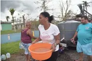  ?? HECTOR RETAMAL/AFP/GETTY IMAGES ?? A woman carries water from a tank in Vega Baja, Puerto Rico, on Saturday. Many on the island lack clean drinking water after Hurricane Maria.